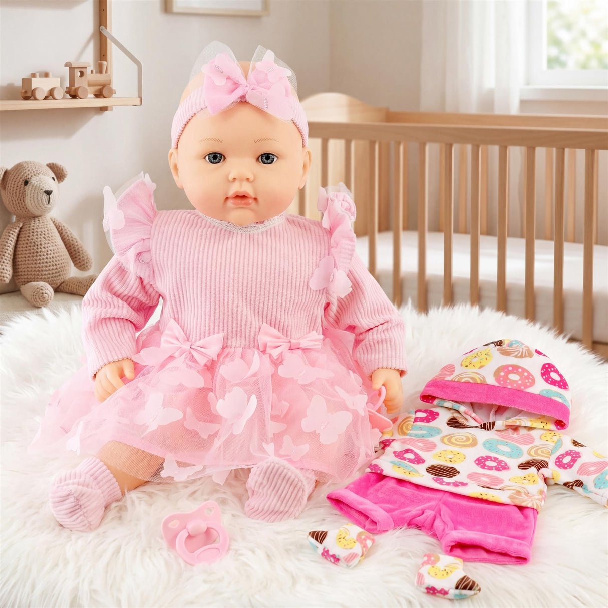 Pink doll in layered pink dress sits on white rug with coordinating clothes and stuffed bear.