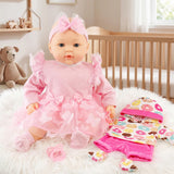 Pink doll in layered pink dress sits on white rug with coordinating clothes and stuffed bear.