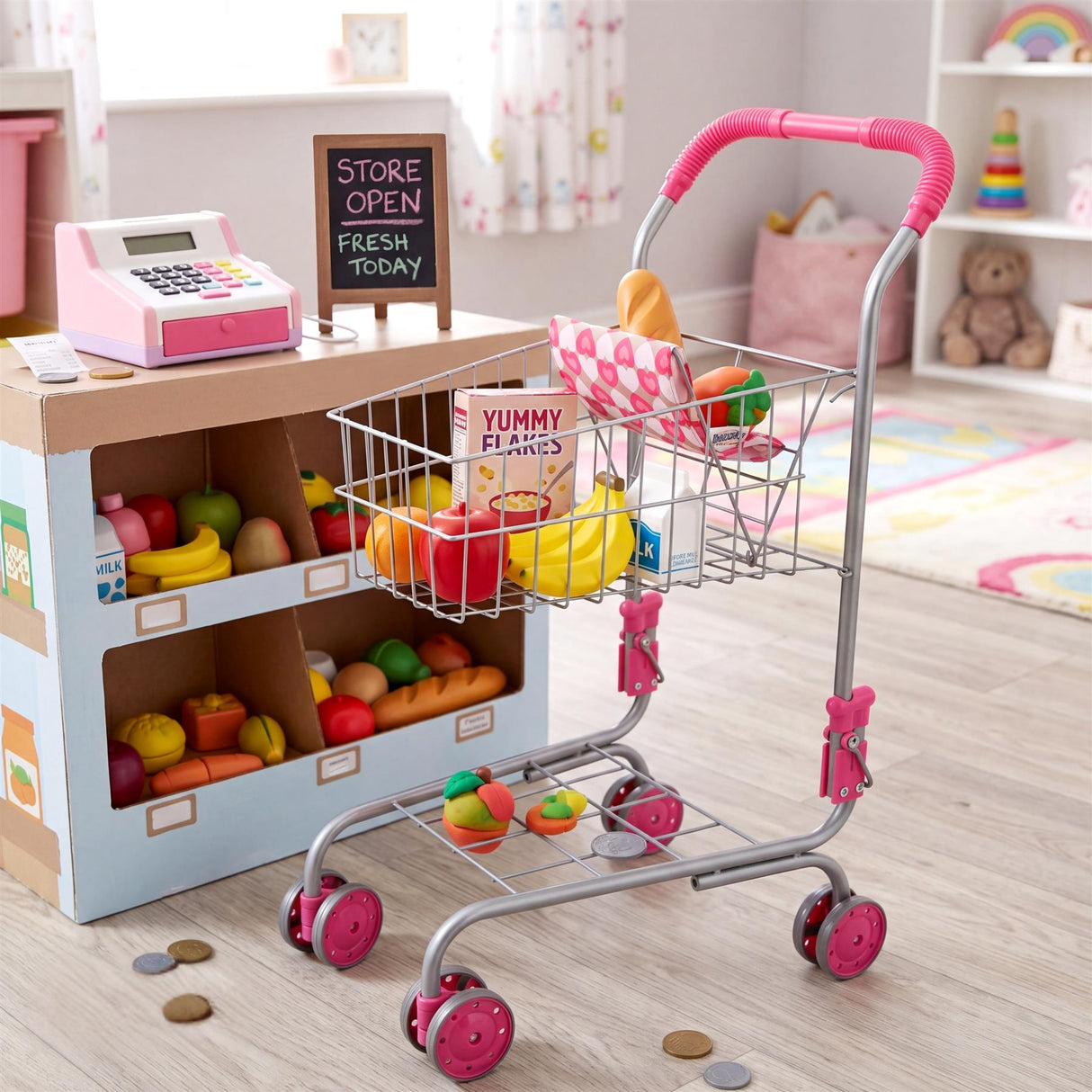 Metal shopping trolley next to a play grocery store counter filled with plastic fruit and toys.