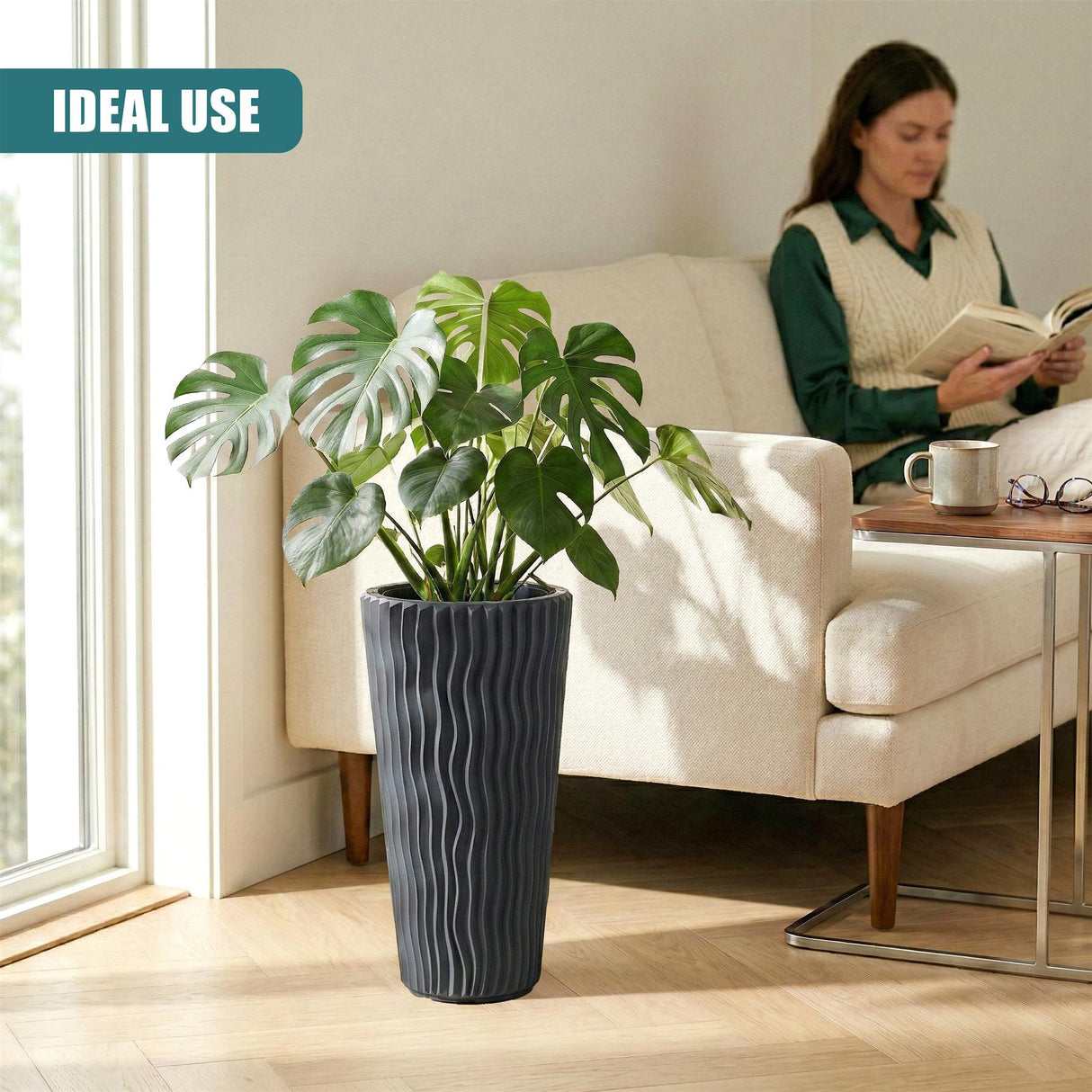 Tall, ribbed, anthracite flower pot displays a large, lush green tropical plant inside.
