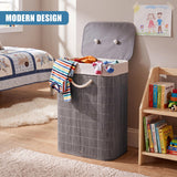 A grey bamboo laundry hamper with a lid and rope handle, filled with clothes, sits on a wooden floor next to a bookshelf in