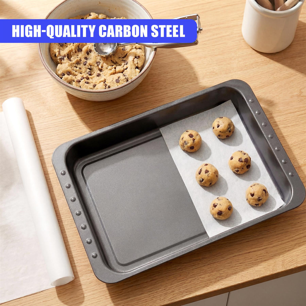 A rectangular dark gray metal roasting pan contains several baked cookies resting on white parchment paper.