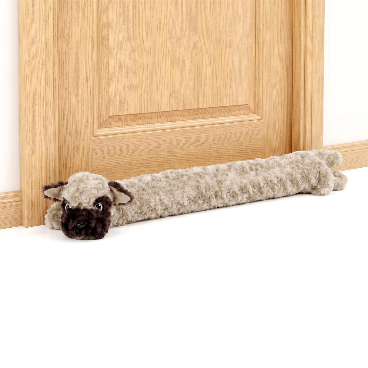 Fuzzy, stuffed sheep draught excluder lying on the floor by a light wood door.