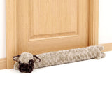 Fuzzy, stuffed sheep draught excluder lying on the floor by a light wood door.