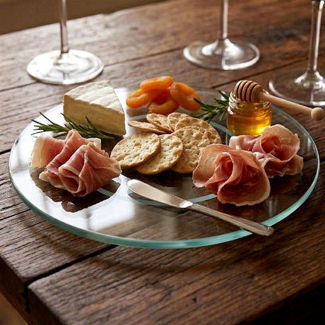 Glass turntable holding charcuterie items: ham, cheese, crackers, honey, and preserved apricots.