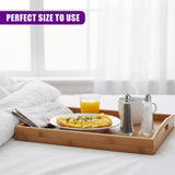 Two clear salt and pepper shakers sit on a wooden tray alongside a cup of coffee.