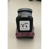 A black and pink plastic toy train engine with cartoon eyes printed on the front.