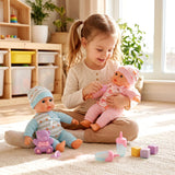 A girl plays with two dolls, miniature accessories, and colorful play items on a carpet.