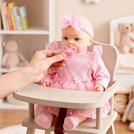 Hand holds pink pacifier near a doll dressed in pink, seated in a baby rocking chair.