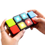 Hands manipulating a compact, multi-colored, square puzzle game or magic cube.