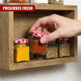 A hand displays a spice jar in a wooden rack with multiple filled spice containers.