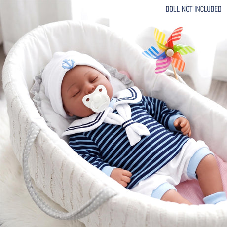 A reborn doll dressed in a striped blue and white sailor outfit lying in a white baby bassinet.