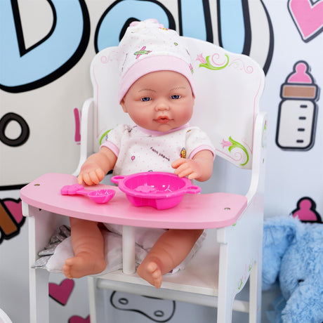 A doll baby in pink clothing sitting on a pink high chair with a bowl of food in front of it.