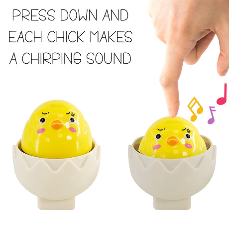Two yellow chick toys in white egg cups. A hand points toward the chick on the right.