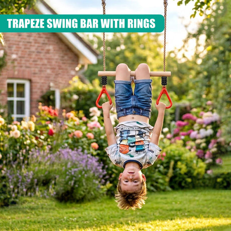 A child hangs from a wooden trapeze bar featuring red rings, set in a lush backyard garden.