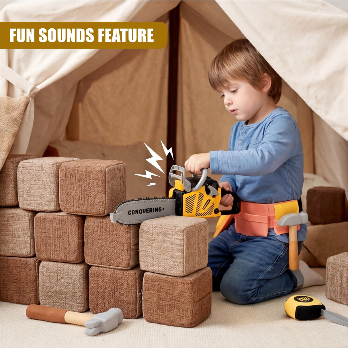 Young boy operating a toy chainsaw among stacked blocks inside a draped tent structure.