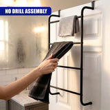 Black towel rail mounted on a white door, holding multiple hanging towels and a towel being added.
