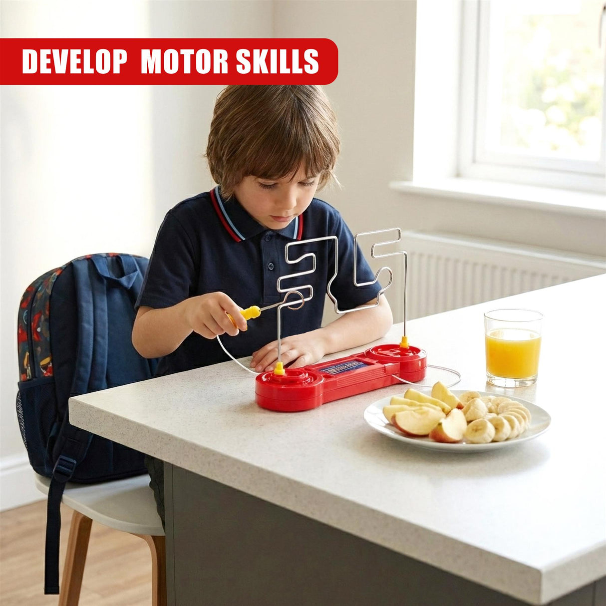 A young boy plays a red wire game set on a kitchen counter near a plate of apples and juice.