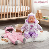 Doll wearing purple patterned clothes rests next to a plush pink hooded outfit and stuffed bear.