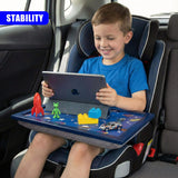 A blue lap tray attached to a car seat holds a tablet and various plastic toys for a young boy.
