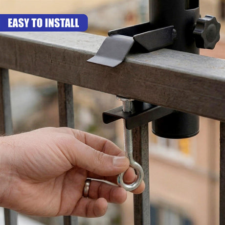A person's hand holds a metal hook attached to a clamp installed on a gray metal railing.