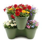 A grouping of green planters filled with various colorful blooming flowers.