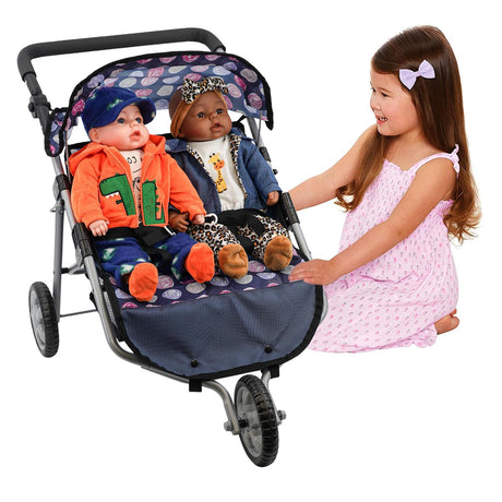 A young girl stands next to a blue double stroller containing two seated doll figures.