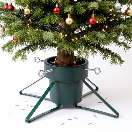 A green metal Christmas tree stand holding a decorated tree against a white background