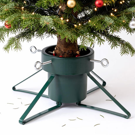 A green metal Christmas tree stand holding a decorated tree, featuring four adjustable bolts and a water reservoir base