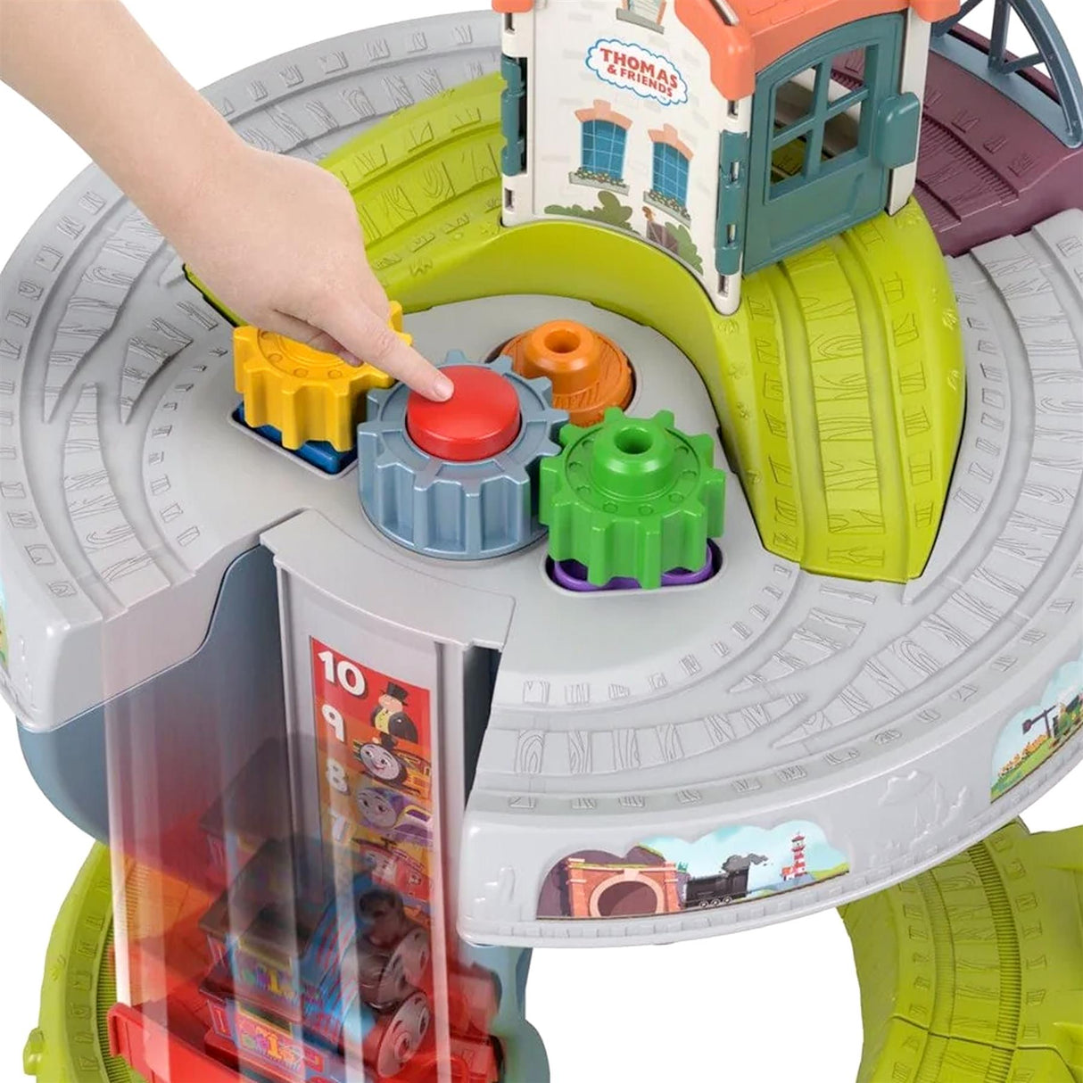 Child's hand places colored connector piece onto a train track on the play table.