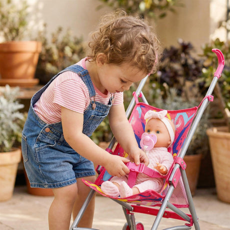 Child interacting with a pink doll buggy containing a baby doll on an outdoor patio.