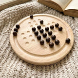 Wooden solitaire board game with multiple indentations and dark wooden playing tokens scattered on it.