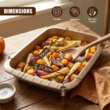 A rectangular roasting tin filled with roasted vegetables and a wooden spoon rests on a wooden surface.