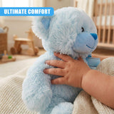 A soft, cuddly blue teddy bear with a smiling face, held by a child's hand, sitting on a white blanket. - UKBuyZone