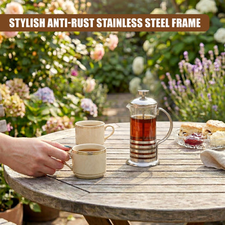Stainless steel cafetiere and small coffee cup rest on a weathered wooden outdoor table.