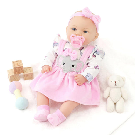 A doll in a pink dress lies with wooden blocks, a teddy bear, and a blue pacifier nearby.