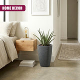 Cylindrical gray planter holding a spiky green plant is displayed near a wooden nightstand.