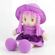 A purple rag doll with pink yarn hair, wearing a wide-brimmed hat and a sparkling purple dress.