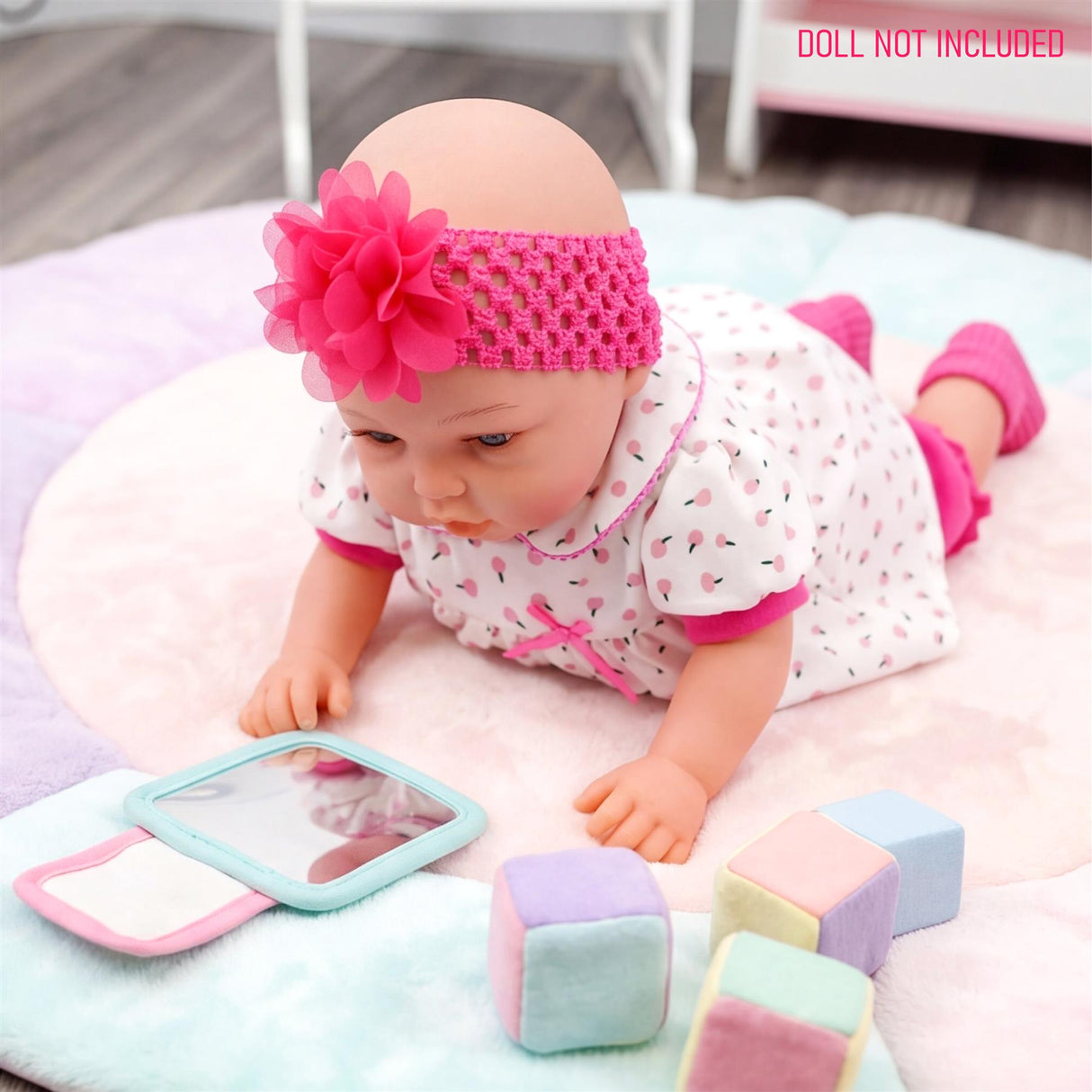 A doll wears a patterned sleeper and pink floral headband, resting among pastel colored blocks.