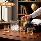 Four whiskey glasses and a clear ice bucket are displayed on a rectangular brown surface.