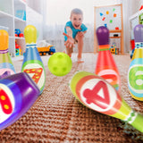 A young boy plays with a colorful plastic bowling set and ball on a patterned carpet.