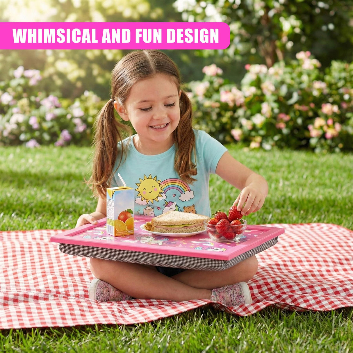 A lap tray featuring rainbow and unicorn patterns holds snacks and beverages on a blanket.
