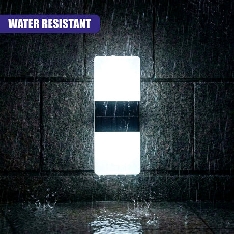 Illuminated rectangular wall light with a central dark panel, mounted on wet, textured masonry.