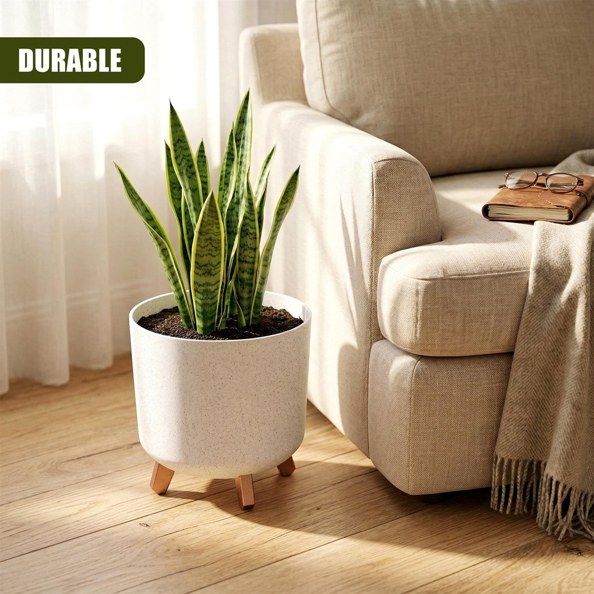 White cylindrical flower pot with small wooden legs holds a vibrant green snake plant on a wooden floor.
