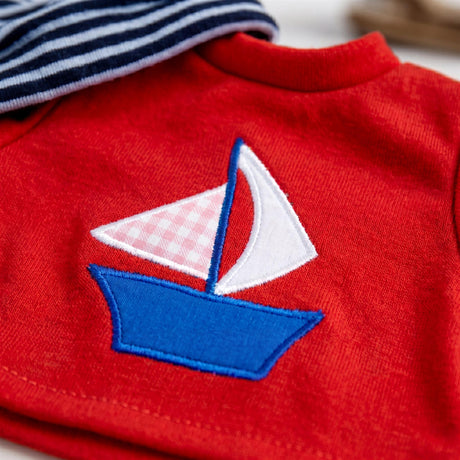 Red knit top features a stylized embroidered sailboat with red and white sails.