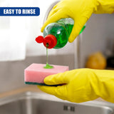 Yellow-gloved hands squeeze soap onto a pink cleaning sponge in a kitchen sink.