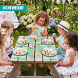 Multiple children use a green and pastel picnic set on a wooden table in a lush garden setting.