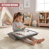 Young girl drawing with crayons on a patterned lap tray cushion resting on a rug.
