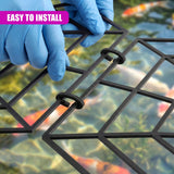 Hands in blue gloves place a grid pond protector into the water.