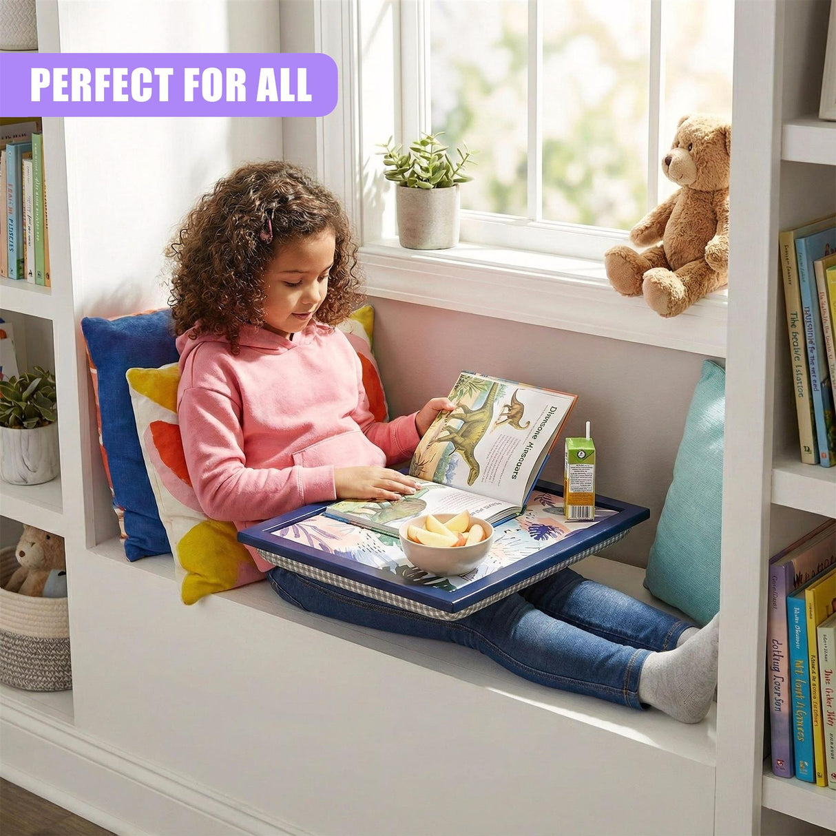 A child sitting in a built-in reading nook, surrounded by books and pillows, reading a book while using a tray with a book, snack, and drink. The child is holding a book and has a snack and drink on the tray. The built-in reading nook has a window seat with a window and a view of the outside. The child is sitting on a pillow and has a book and snack on a tray. - UKBuyZone